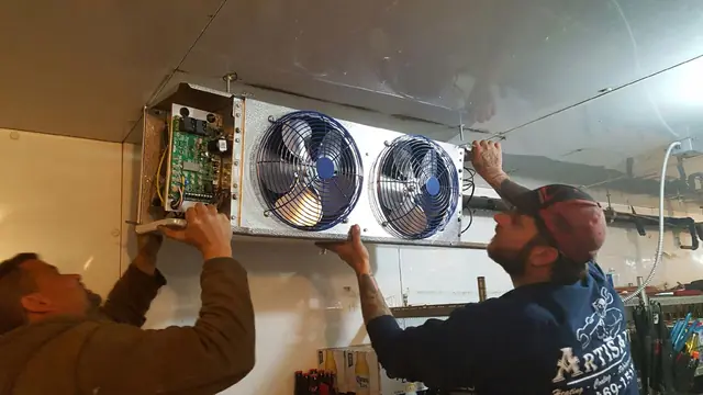 Artisan technicians mounting a new evaporator inside a walk-in cooler