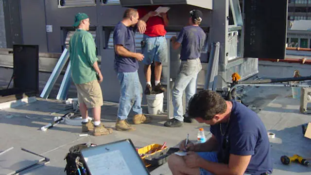 Crew reviewing paperwork beside a large rooftop unit