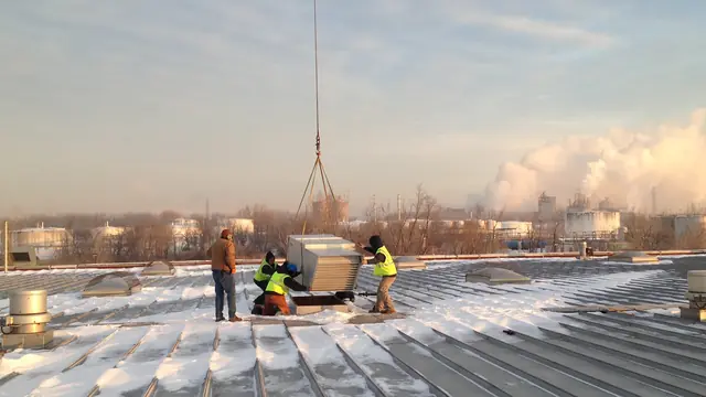 Rooftop unit being lowered into place while the crew stands by